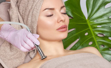 Obraz na płótnie Canvas The cosmetologist makes the procedure Microdermabrasion on shoulders, neck and collarbone of a beautiful woman in a beauty salon.Cosmetology and professional skin care.