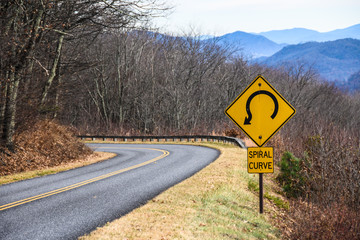 Yellow Spiral Curve Sign Along a Mountain Roadway