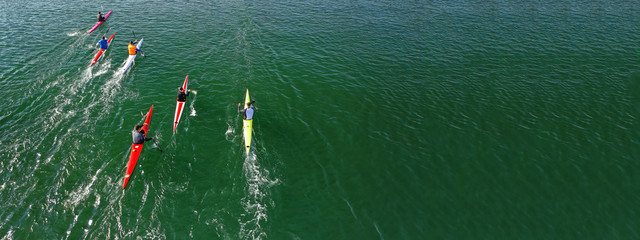 Aerial drone ultra wide photo of young athletes rowing in canoe competition in tropical lake with...