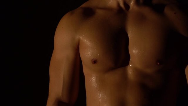 Young man muscular body torso close-up dark background chest