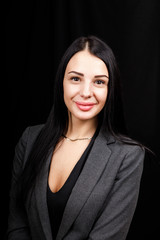 Portrait of young business woman in 
a grey jacket on black background