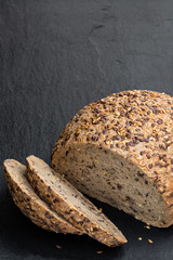 Gluten free multi seed bread with linseed on black stone background
