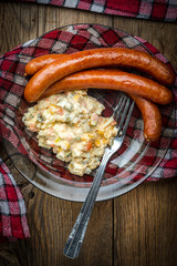 Thin sausages with vegetable salad on plate.