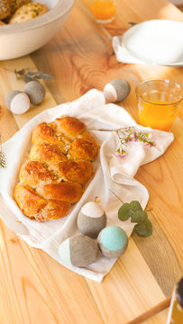 Easter table laid for Easter breakfast Easter Sunday in sunlight orange juice and Easter braid pastries interior decoration concrete Easter eggs natural and sustainable decoration