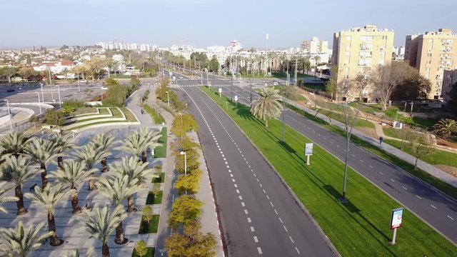 Moving in air from left to right over Beer-Sheva street with crossroad, fountain and palm grove