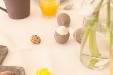 white tablecloth laid on easter table for easter breakfast orange juice and narcissus flowers interior decoration concrete easter eggs natural and sustainable decoration