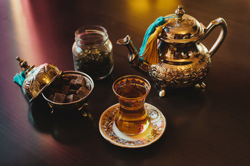 Teapot, sugar, tea glasses and mint on a brown table