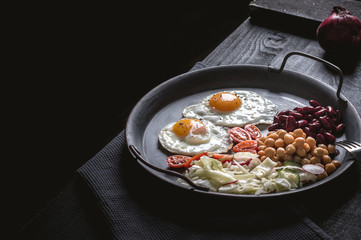 Close-up of sunny side up eggs with vegetables on dark background