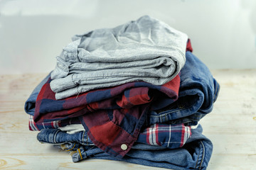 stack of clean clothes or dirty laundry, jeans, plaid shirt, t-shirt