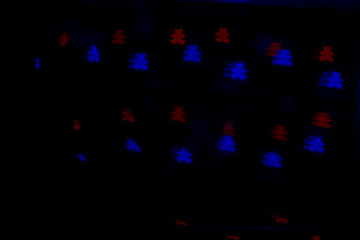 Bokeh in the form of bears of red and blue colors on a dark background