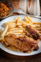 Roasted chicken with french fries on a plate.