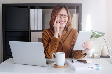 asian adult entrepreneur work on laptop and mobile phone with paperwork in the smart office
