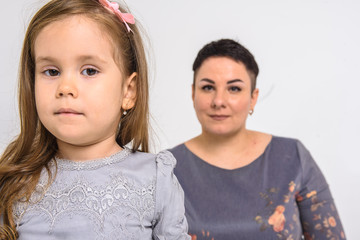 Emotional portrait of mom with daughter dressed in gray dress, on white background
