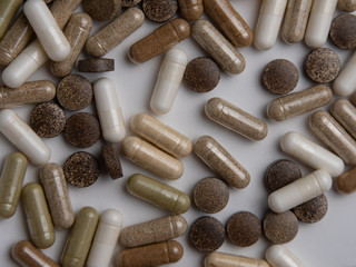 many different pills and capsules on a white table, top view