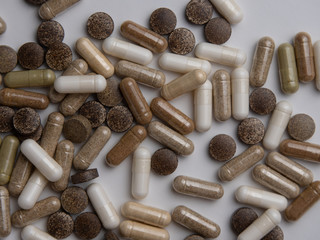 many different pills and capsules lie on a white table, top view