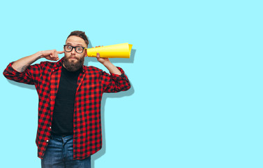 Handsome hipster guy secretly listening through yellow tube rolled up paper. Your text here! Discount, sale, season sales.