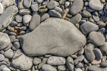 Large flat rock on pebble filled beach - suitable for text