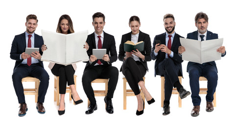 Obraz premium Team of 6 reading from book, phone, tablets and newspapers