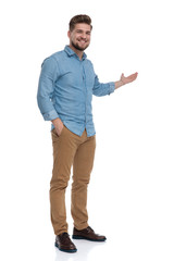 Smiling casual man presenting with his hand in his pocket