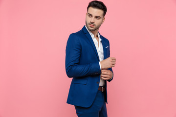 Young businessman adjusting his sleeve and looking away