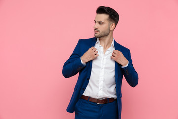 Confident businessman adjusting his jacket and looking away