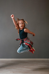 Fototapeta na wymiar Active child. Full length portrait of a cute little girl in casual clothes jumping in the dance studio