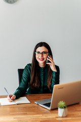 Woman works with a laptop and talks on a phone