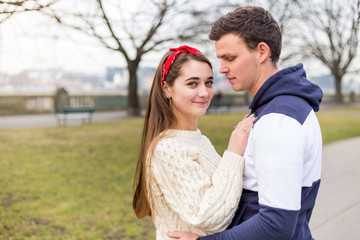 Young couple in love outdoor. Cute couple of young people is walking in spring park. Happy guy and girl. They are looking at the camera.