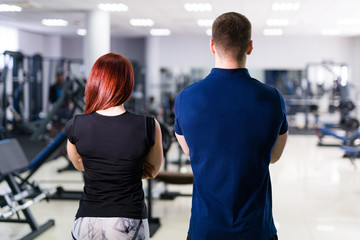 Fototapeta na wymiar Back view of muscular sport people in half height standing crosshands over the gym background. Portrait of a strong sportswomen.