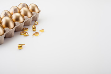 Golden eggs in a cassette, on the edge of a white background with space for text, candy decorations. The concept of Easter, the egg as a religious symbol or abundance.