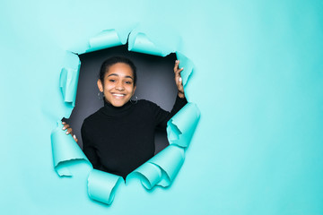 Young smile latin woman posing from green paper hole