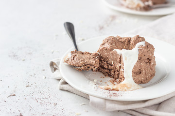 Chocolate cottage cheese dessert decorated with white chocolate glaze, coconut flakes and cocoa powder, light grey stone background. 