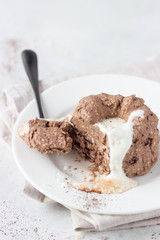 Chocolate cottage cheese dessert decorated with white chocolate glaze, coconut flakes and cocoa powder, light grey stone background. 