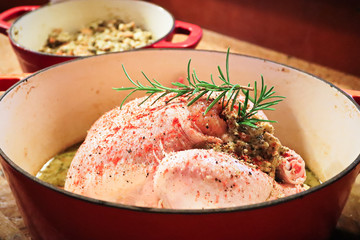 Side view of a raw chicken with stuffing in a pot