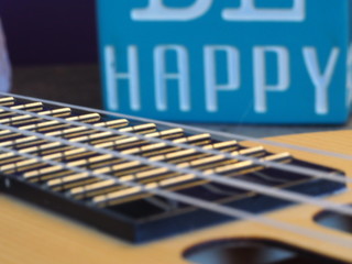 Ukulele Strings Close Up with a Be Happy Sign in Background