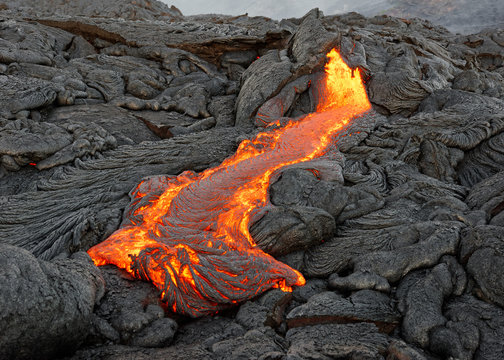 Hot magma of an active lava flow emerges from a fissure, the heat of the glowing lava makes the air flicker, the lava cools down slowly and solidifies - Hawaii, Big Island, Kilauea volcano, Kalapana