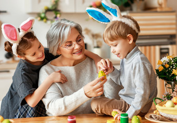 Happy easter! family grandmother and children grandchildren paint eggs for holiday.