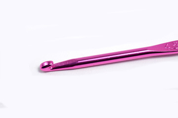 Pink metal crochet hook for knitting craft on an isolated white background