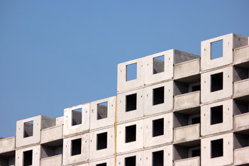 Unfinished skyscraper under construction. Cement building, blue sky background.