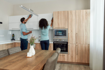 Clean it up. Back view of two young professional cleaners in uniform cleaning modern kitchen...
