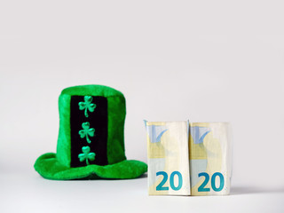 Green hat with shamrock two euro banknotes folded making 2020 year Saint Patrick day celebration. Bright background, copy space.