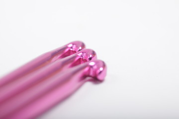 Pink metal crochet hook for knitting craft on an isolated white background