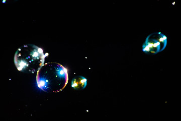 Multicolored soap bubbles with highlights on a dark background