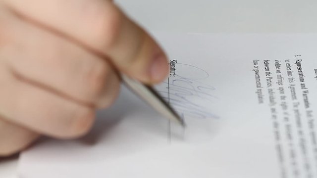 Closeup shot of a business man signing a contract, legal agreement or paper. Man is approve documents by signing papers.