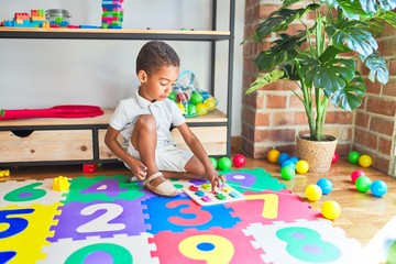 Beautiful african american toddler playing with maths game using numbers at kindergarten