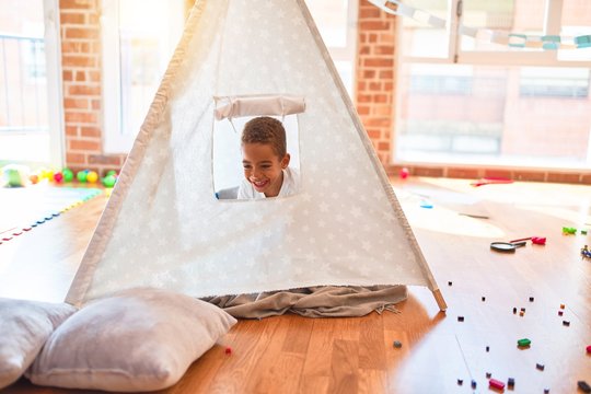 Beautiful african american toddler playing inside tipi smiling at kindergarten