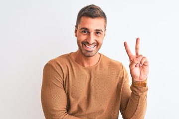 Young handsome elegant man wearing winter sweater over isolated background smiling with happy face winking at the camera doing victory sign. Number two.