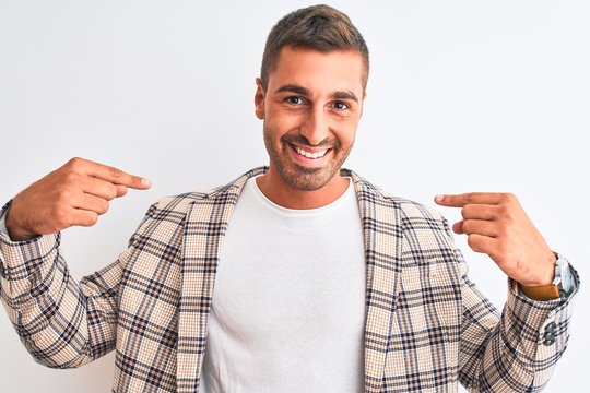 Young handsome business man wearing elegant jacket over isolated background looking confident with smile on face, pointing oneself with fingers proud and happy.