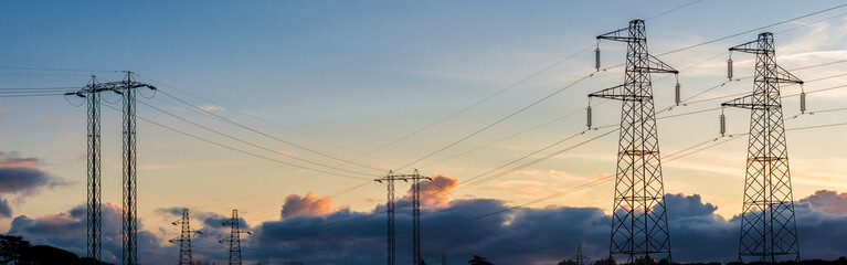 Energy power cables. Transmission towers or electricity pylons with sunset sky