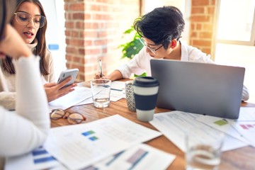 Beautiful businesswomen smiling happy. Sitting with smile on face working using smartphone and laptop at the office